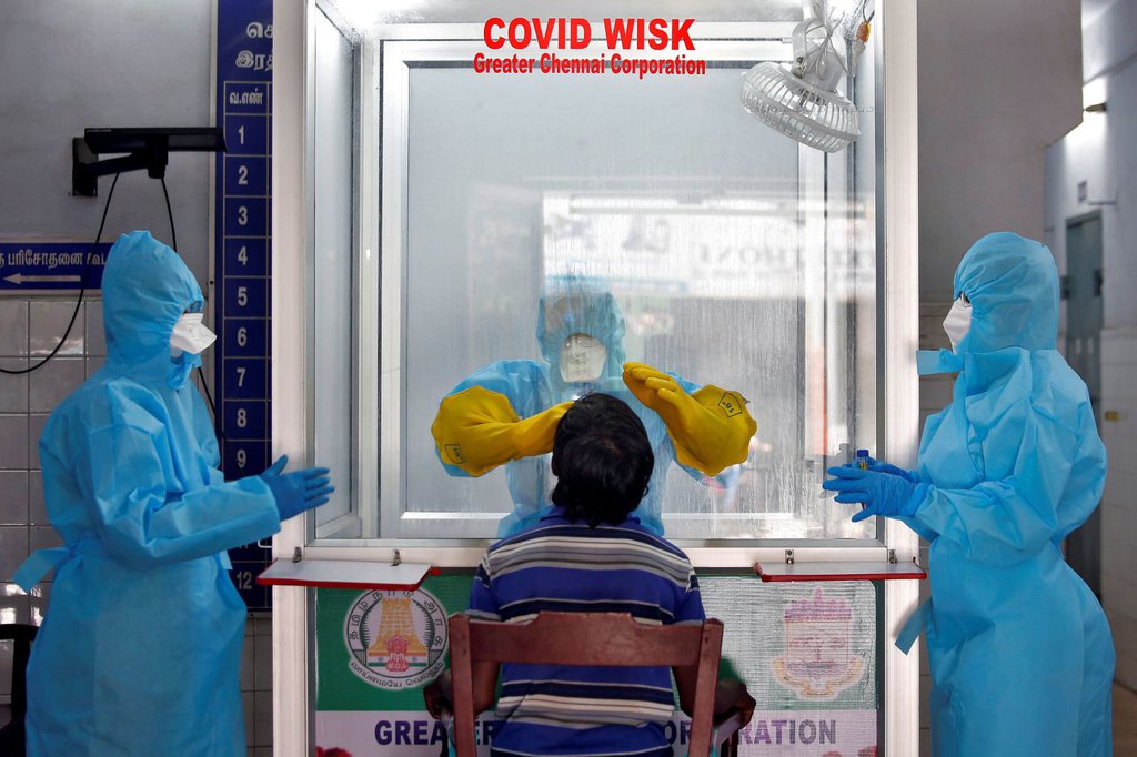 A doctor in a protective chamber tests a patient for coronavirus at a walk-in kiosk in Chennai, India, on April 13.P. Ravikumar-Reuters.jpg