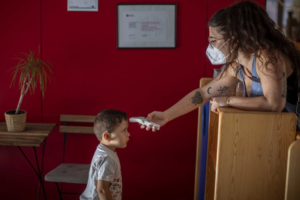 Hugo, 3, has his temperature taken by a teacher as he arrives at kindergarten in Barcelona on June 26.Emilio Morenatti-AP.jpg