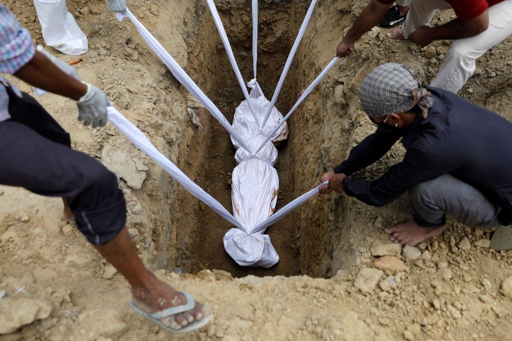 A coronavirus victim is lowered into the ground during her funeral in New Delhi on August 7.Adnan Abid-Reuters.jpg