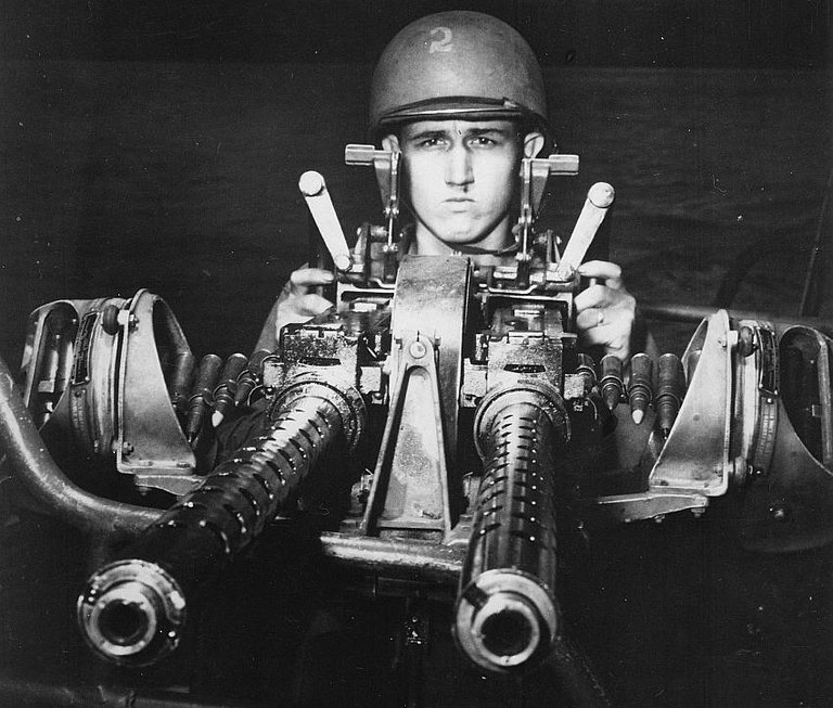 An American torpedo boat marksman behind his machine gun off the coast of New Guinea, July 1943..jpg