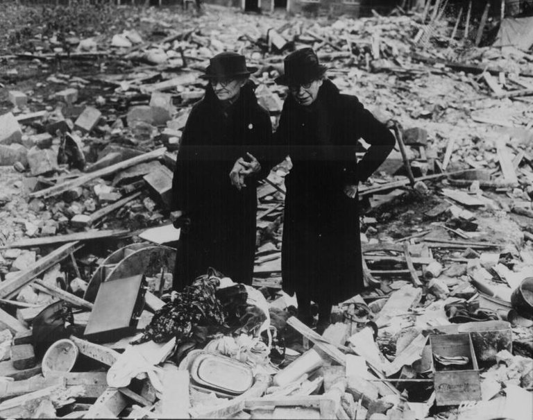 Two women stand amid the leveled ruins of the almshouse that was their home before a German bombing raid destroyed it in Newbury, England on February 11, 1943..jpg